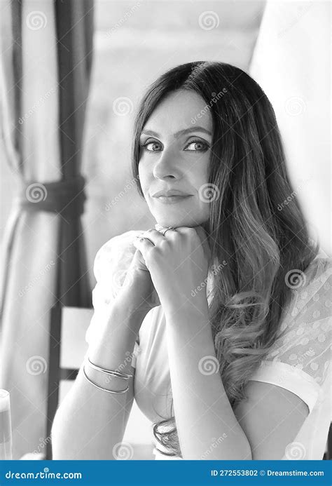 Black And White Portrait Of A Beautiful Brunette Girl In A White T Shirt With Blue Eyes Sitting
