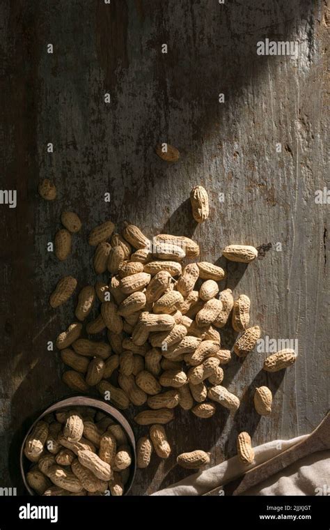 Pile Of Unpeeled Peanuts On A Wooden Background With Old Cup Also