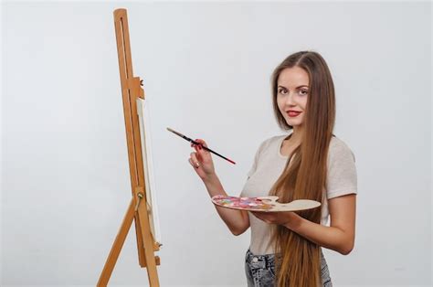 Premium Photo Girl Artist Paints Picture On An Easel With Brush And