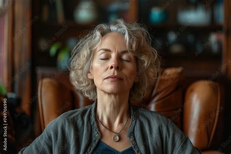 Middle Aged Woman Meditating At Home With Eyes Closed Relaxing Body