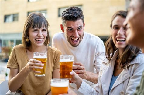 Grupo de amigos bebendo cervejas e rindo pessoas da geração z no pub se