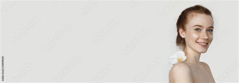 Red Haired Woman With Freckles Is Posing With A Flower On Naked Shoulders And Cream On Face