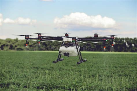 Professional Large Drone Spray Water Over A Green Field Stock Photo