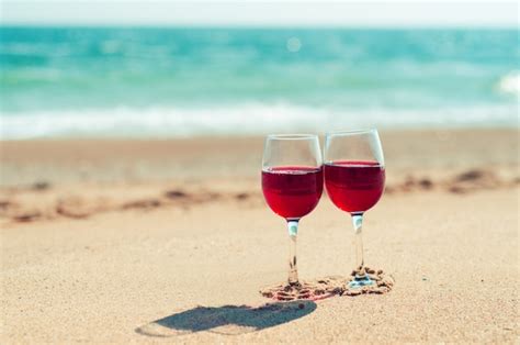 Premium Photo Two Wine Glasses With Red Wine On The Sand Of The Beach