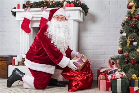 Santa poniendo regalos bajo el árbol de navidad decorado Foto Gratis