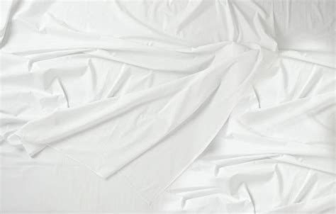 An Unmade Bed With White Sheets And Pillows