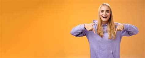 Amusé joyeux jolie petite amie blonde pointant vers le bas présent cool nouveau produit souriant