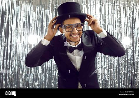 Funny young black man in a dinner suit, top hat and glasses having fun at a party Stock Photo ...