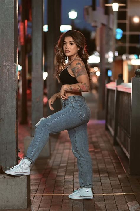 a woman with tattoos is leaning against a pole