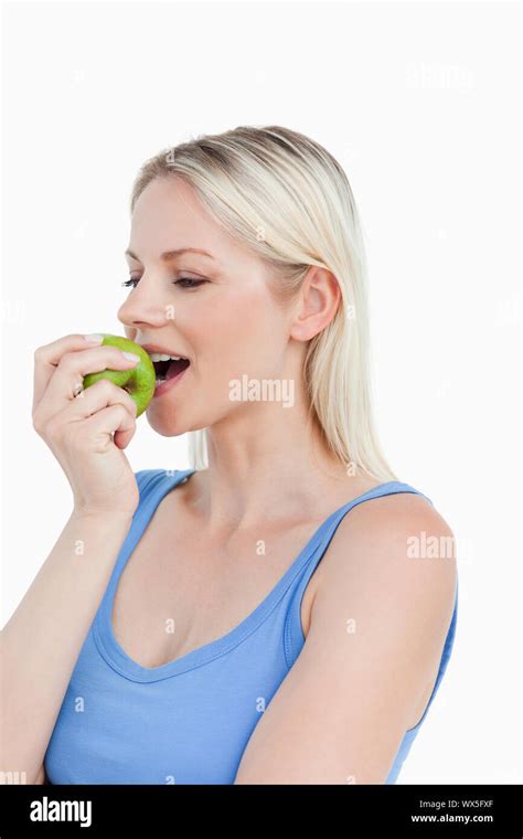 Beautiful Blonde Woman Eating A Green Apple Against A White Background Stock Photo Alamy
