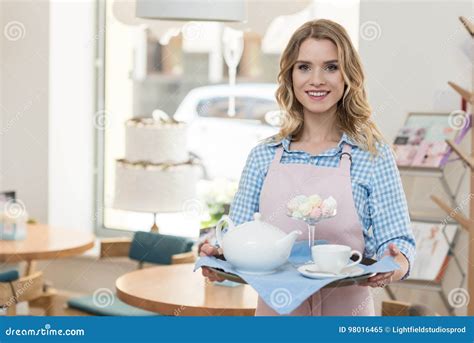 Serveuse Blonde Dans Le Tablier Tenant Le Plateau Avec Le Thé Et Les Biscuits Au Café Image