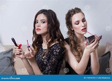 Two Beautiful Girls Sitting On The Sofa Makeup Looks At The Mirror Causing A Pink Red