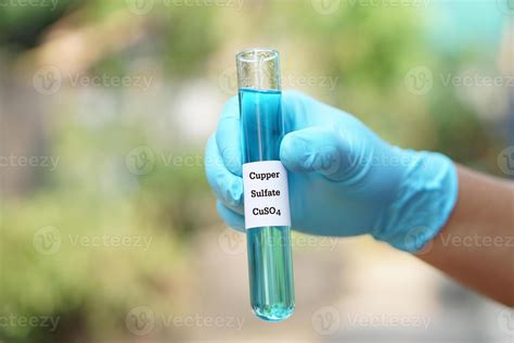 Close up hand wear blue glove, holds test tube of Copper Sulfate liquid