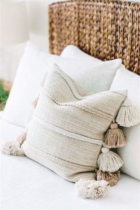 A White Bed Topped With Pillows And A Lamp Next To A Wicker Headboard