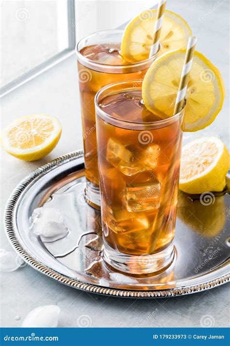 Two Frosty Glasses Of Ice Tea With Lemon Slices On A Metal Tray Against