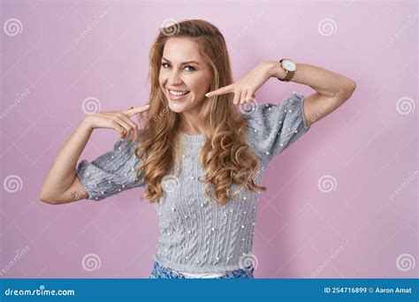 Beautiful Blonde Woman Standing Over Pink Background Smiling Cheerful Showing And Pointing With
