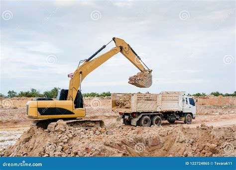 Yellow Excavator Machine Loading Soil Into A Dump Truck At Construction