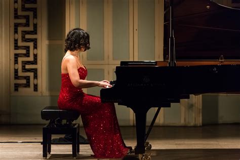 a woman in a red dress sitting at a piano