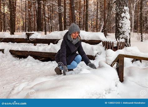 La Fille Blonde Dans Un Chapeau Gris Et Des Gants Et Une Veste D Hiver Se Sont Accroupies Vers