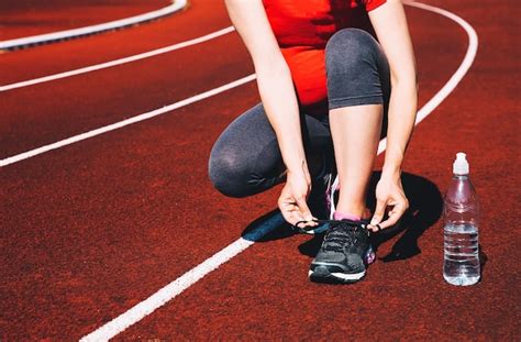 Mulher Esportiva Gr Vida Amarrando T Nis Na Pista De Corrida Vermelha