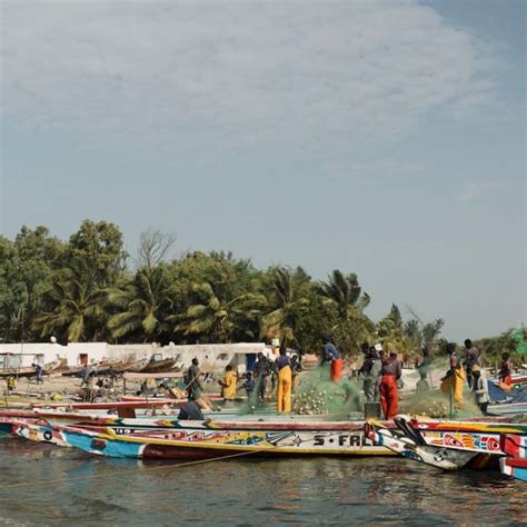 Several Boats With People Standing On Them In The Water Next To Some