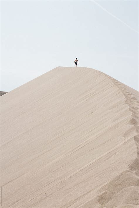 "Young Man Climb To The To Of Sand Dune Mountain Peak" by Stocksy