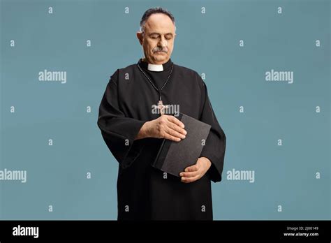 Mature Priest Holding A Bible And Looking Down Isolated On Blue Background Stock Photo Alamy