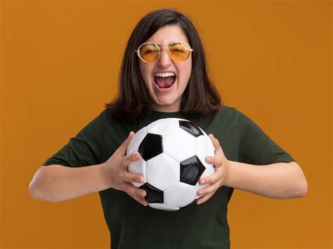 Emocionada joven bastante caucásica en gafas de sol sosteniendo la bola