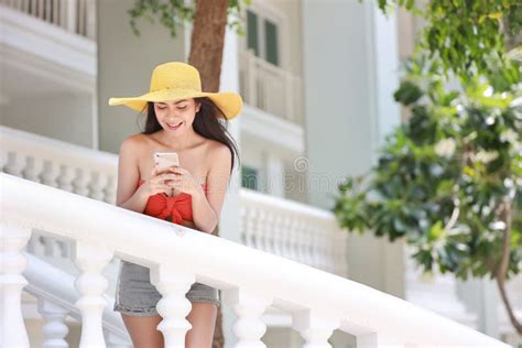 Attractive And Asian Girl In Orange Bikini With Nice Hat Using Cell Phone Do Chatting With Happy