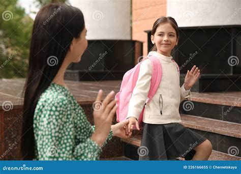 Little Girl Waving Goodbye To Mother Near School Entrance Outdoors ...