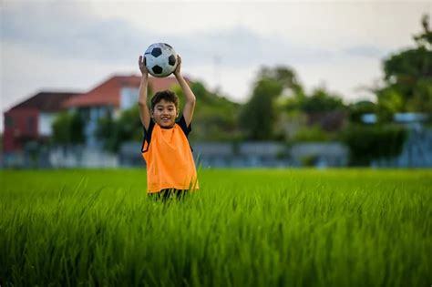 Niño feliz y emocionado de 8 o 9 años jugando al fútbol al aire libre