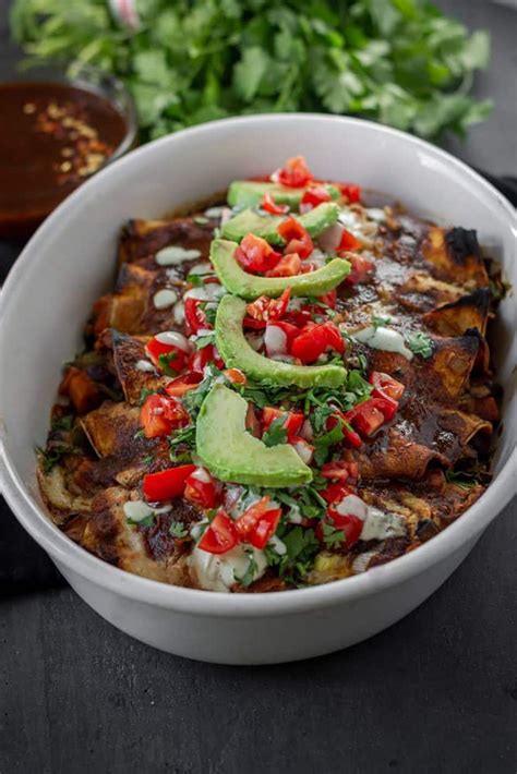 A White Bowl Filled With Mexican Food Next To Cilantro And Avocado