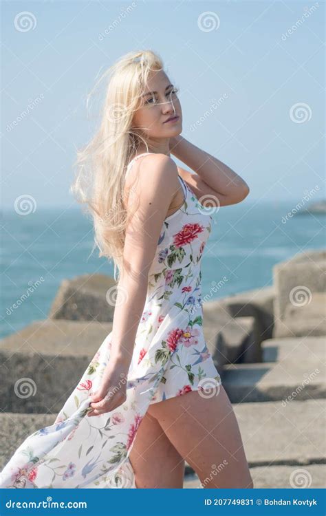 Blonde With Beautiful Legs On The Stones Of The North Sea Beach In A