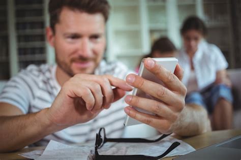 Premium Photo Happy Man Sitting At Table And Using His Mobile Phone