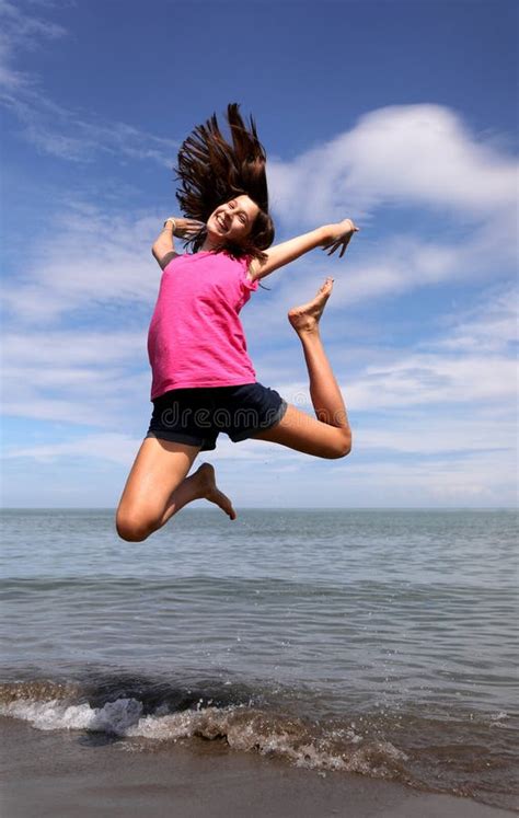 Une Jeune Fille Qui Saute En Haut Pour La Joie Au Bord De L Eau Photo