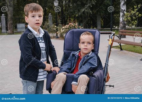 Cerebral Palsy Child on Medical Stroller Walking Outdoors, Brother ...