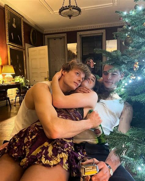 Two People Hugging Each Other In Front Of A Christmas Tree