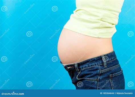 Close Up Of Naked Pregnant Woman`s Belly Wearing Opened Jeans At