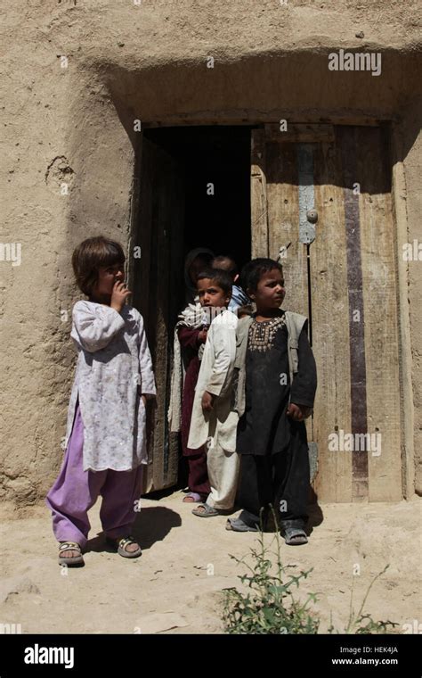 Afghan Children Stand In The Doorway Of Their Home And Watch As A