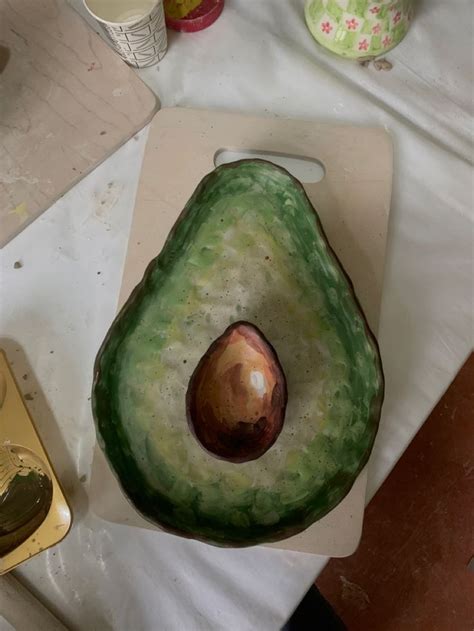 An Avocado Cut In Half Sitting On Top Of A Cutting Board Next To A Knife