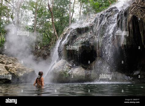 Woman In Bikini Taking A Bath In A Lake Where A Cascade Of Steaming Hot Springs Falls Stock