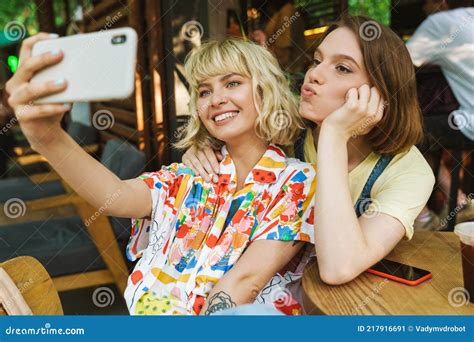 Image Of Two Women Taking Selfie On Cellphone While Sitting In Cafe