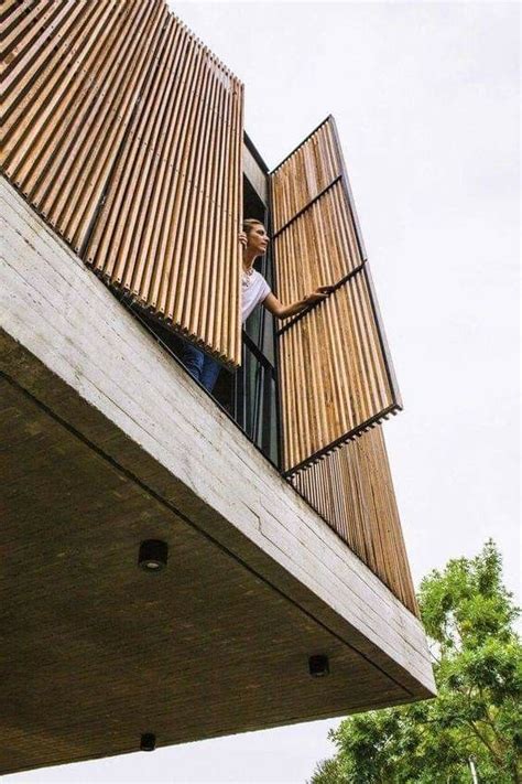 A Man Standing On Top Of A Balcony Next To A Tall Building With Wooden