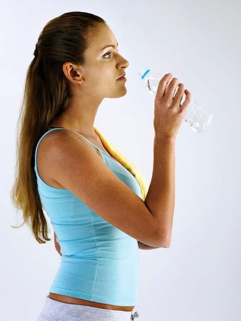 Vista De Perfil De Una Mujer Bebiendo Agua Contra Un Fondo Blanco