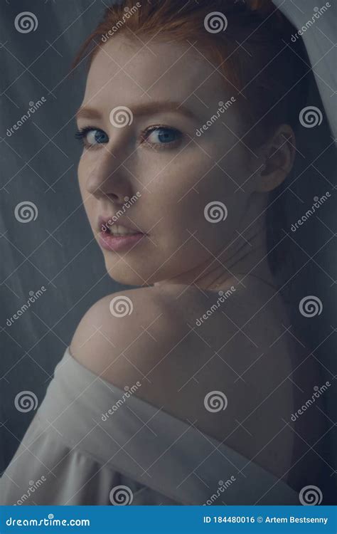 Redhead Girl Looking At The Camera Over Her Naked Shoulder Frame Through The Curtain Stock
