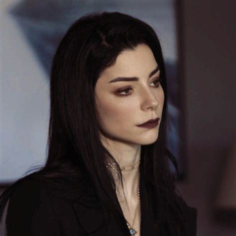 A Woman With Long Black Hair And Dark Makeup Looks Off To The Side