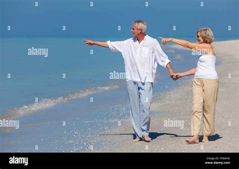 Happy Senior Man And Woman Couple Walking Holding Hands And Pointing