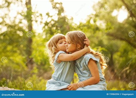 Two Cute Little Sisters. Kiss Stock Photo - Image of park, flowers ...