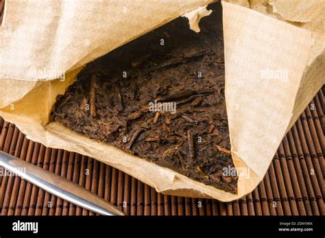 Chinese Pressed PU Erh Tea On Wrapping Paper And Tea Knife On A Bamboo