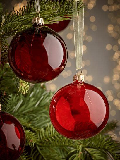 Three Red Ornaments Hanging From A Christmas Tree